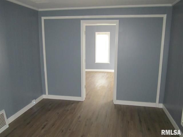 A blue room with white trim, doorway to another room with a window