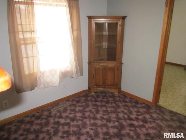 Corner cabinet in a room with a window, brown carpet, and tan walls.