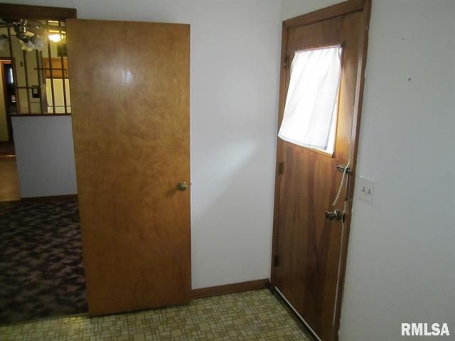 Two wooden doors in a room with a patterned carpet. One door has a curtain over a window.