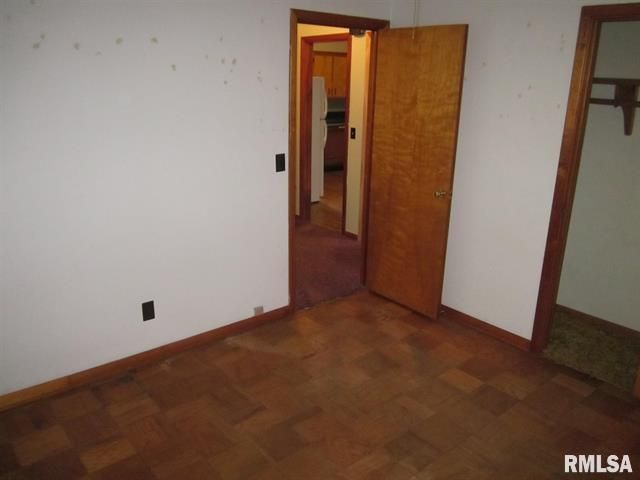 Empty room with wood floors and doors. White walls show water stains.