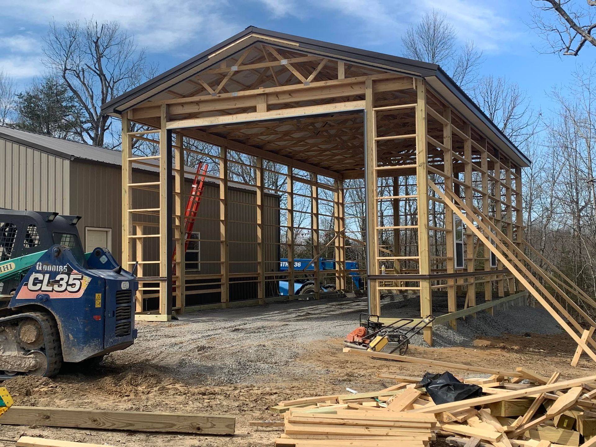 A blue tractor is parked in front of a building under construction.
