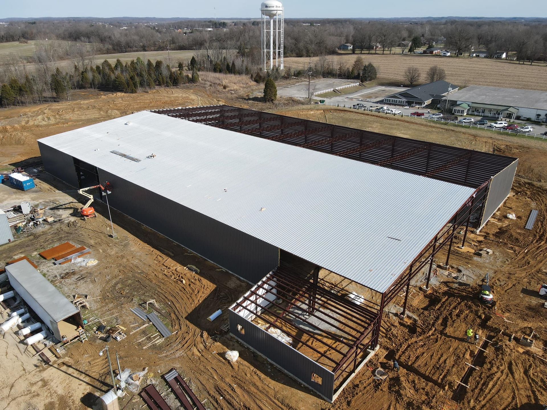 An aerial view of a large building under construction with a water tower in the background.