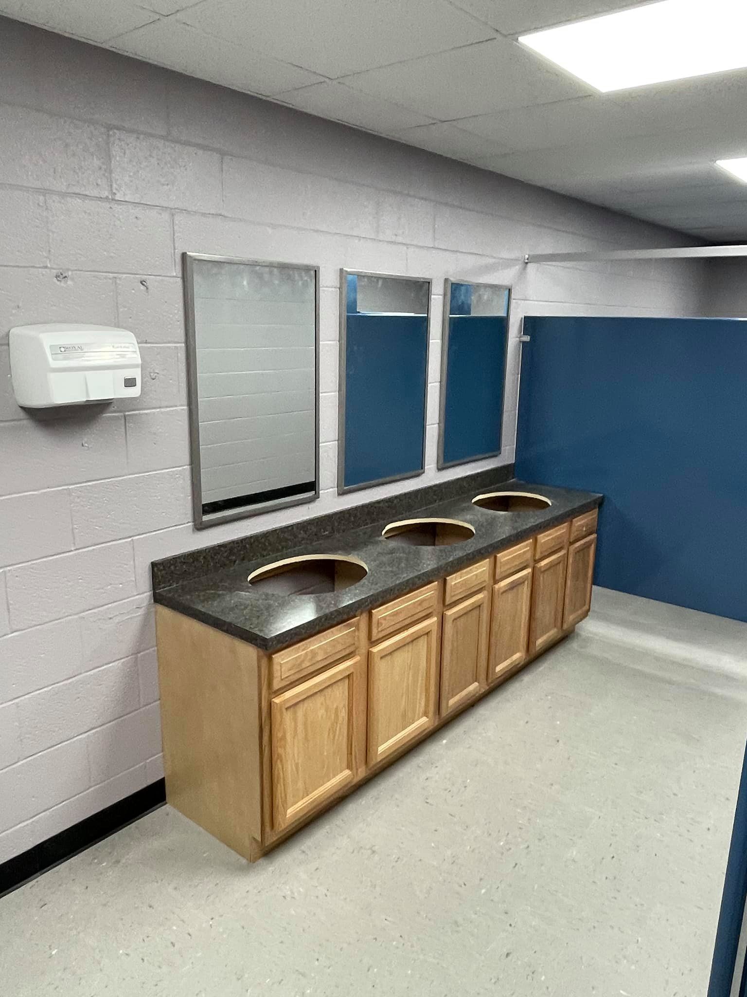 A bathroom with three sinks and three mirrors.