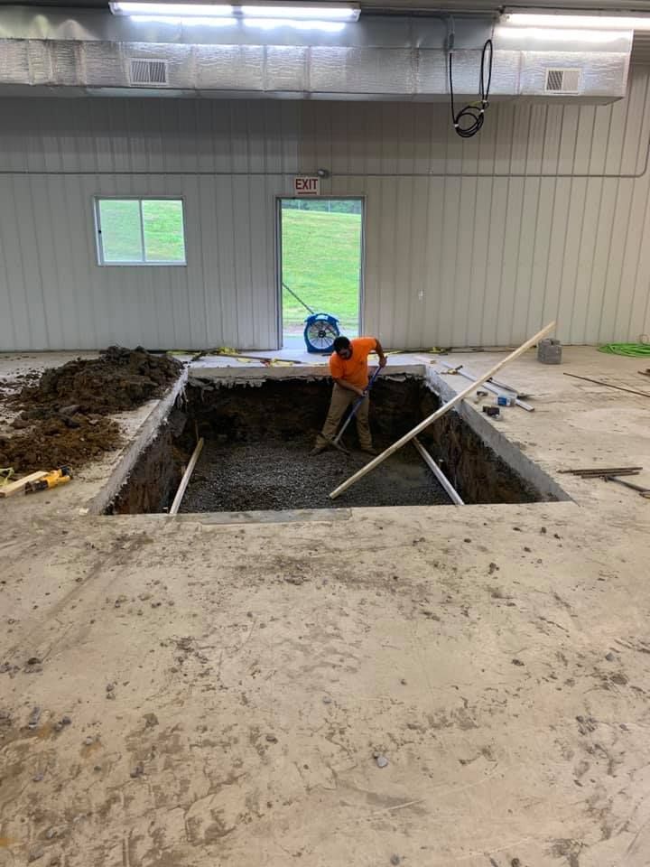 A man is digging a hole in the floor of a building.