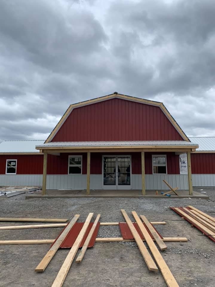 A red barn with a white roof and a porch is being built.