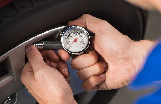 A man is checking the pressure of a tire with a gauge