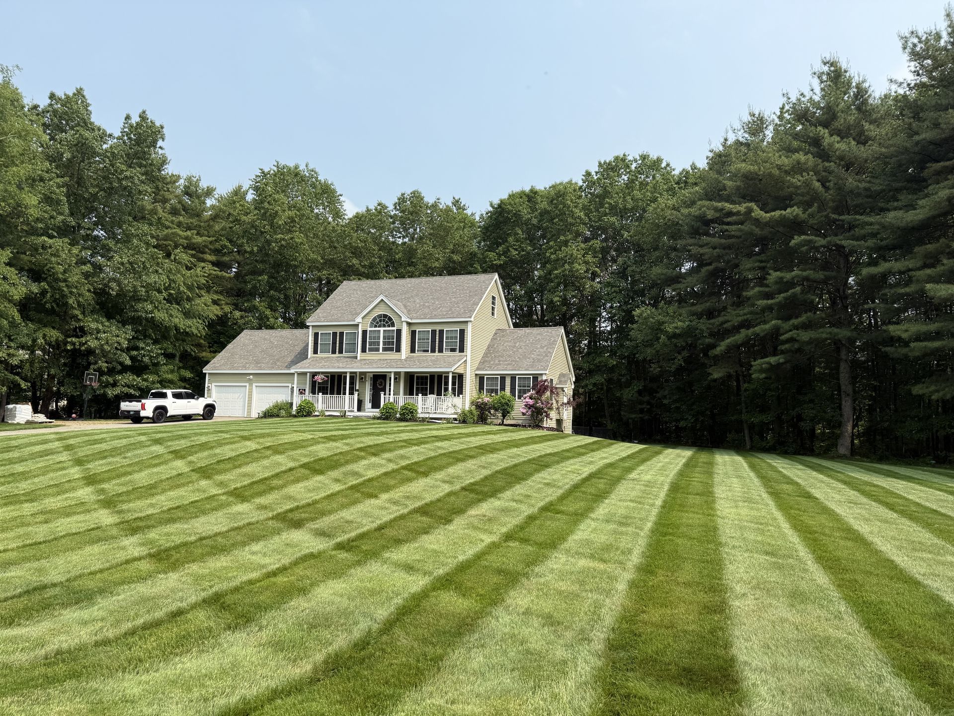 Large white house with a striped green lawn and trees in the background