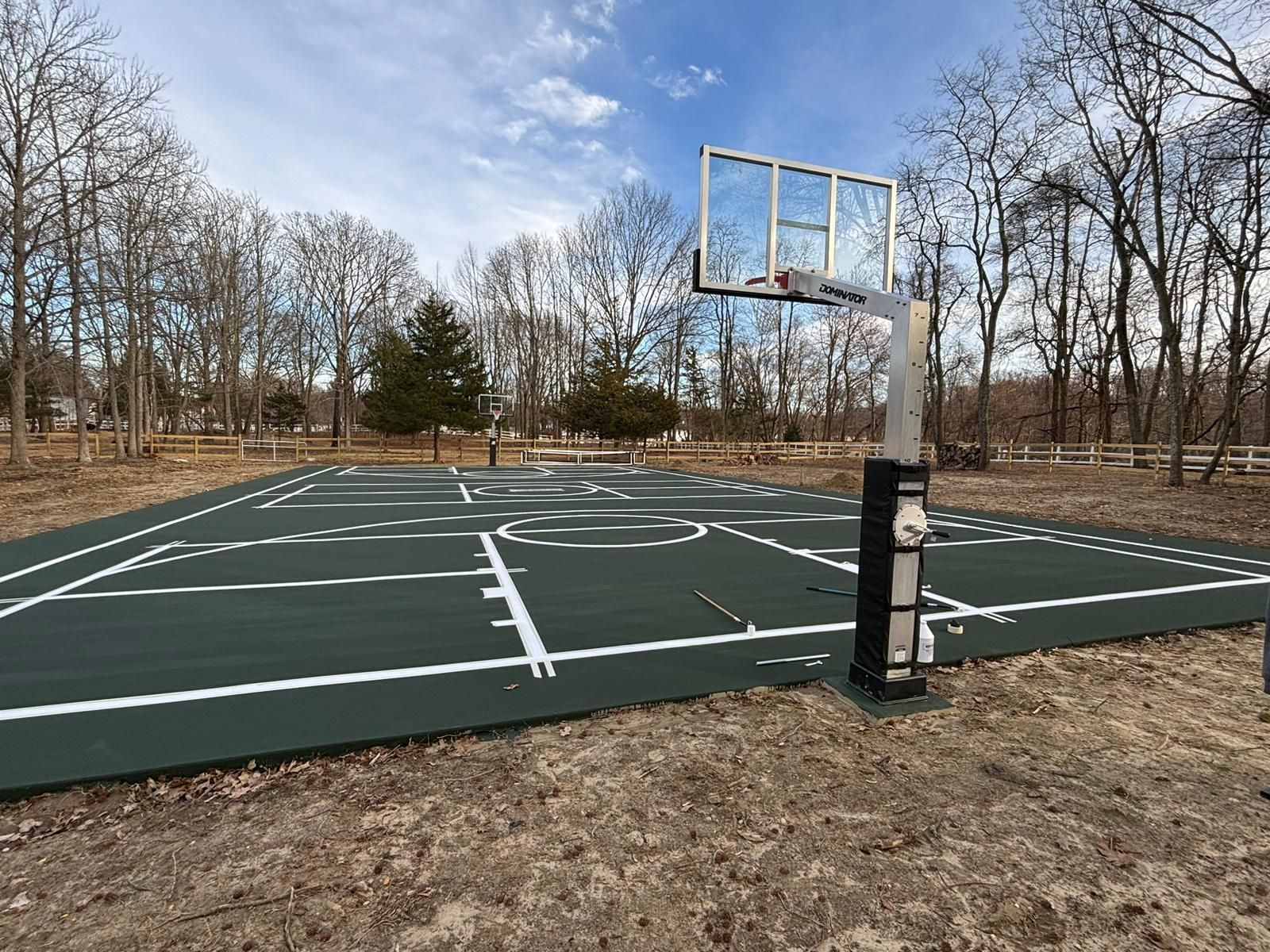 A basketball court in the middle of a field with trees in the background.