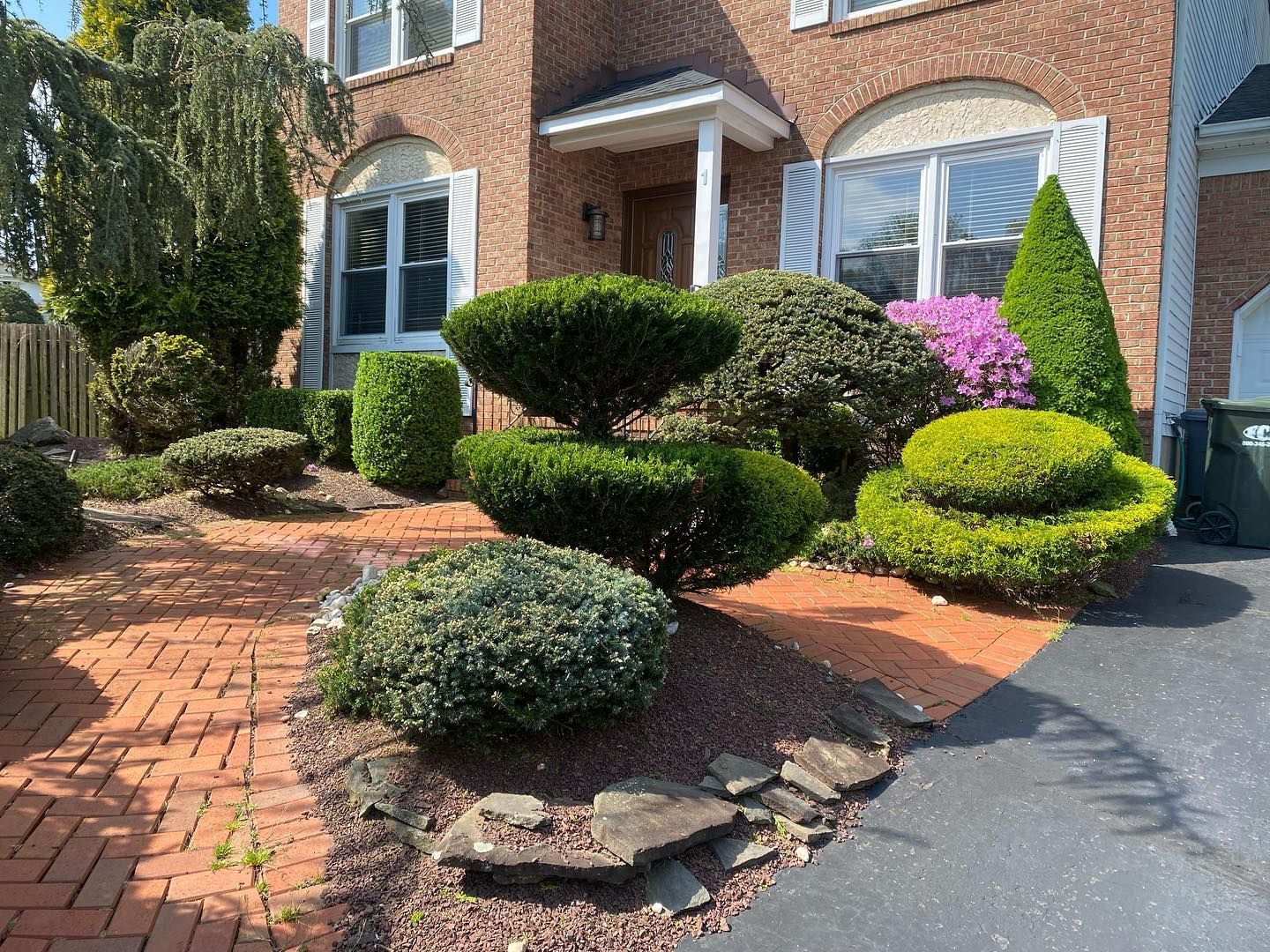 A brick house with a lush green garden in front of it.