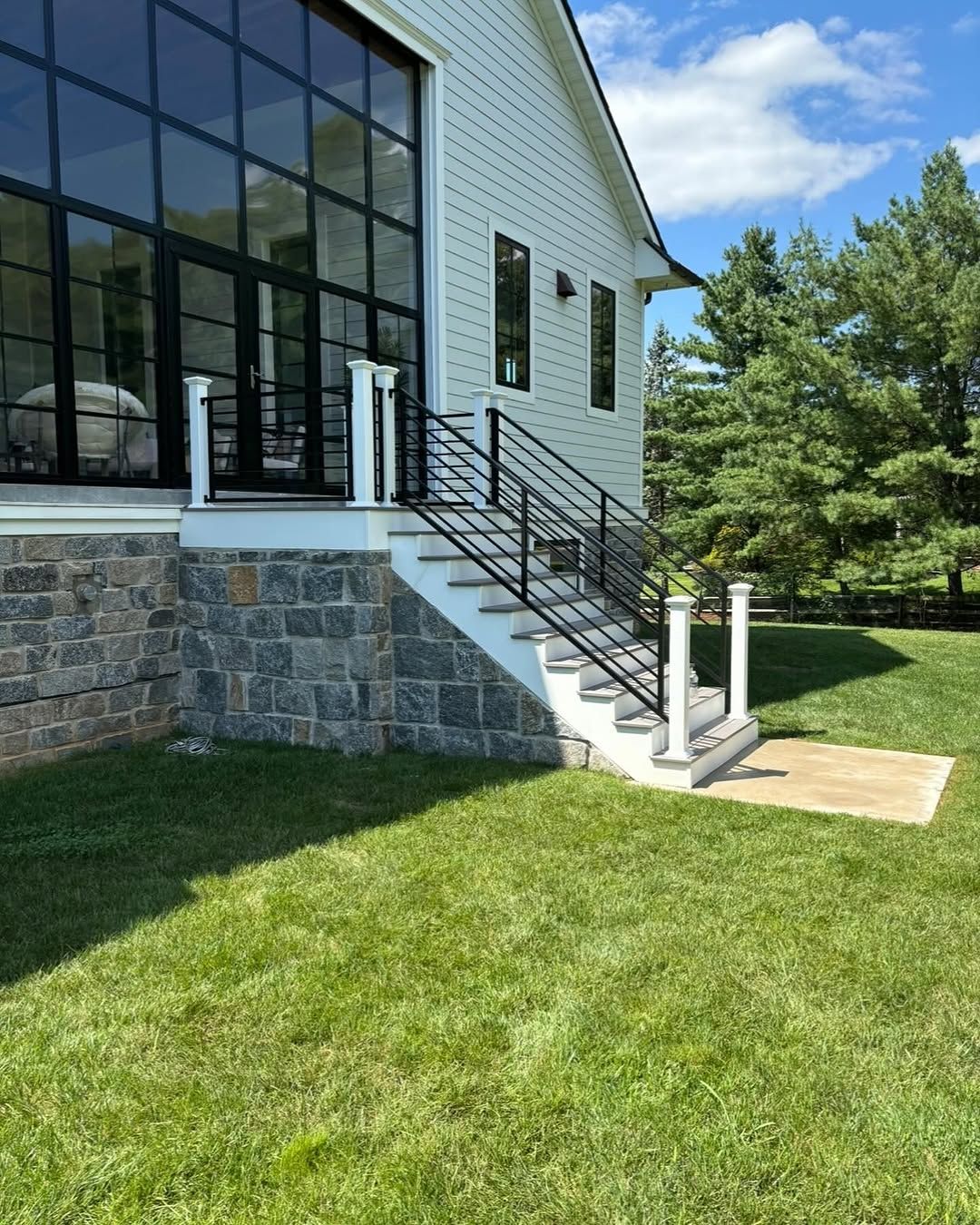 A white house with black windows and stairs leading up to it.