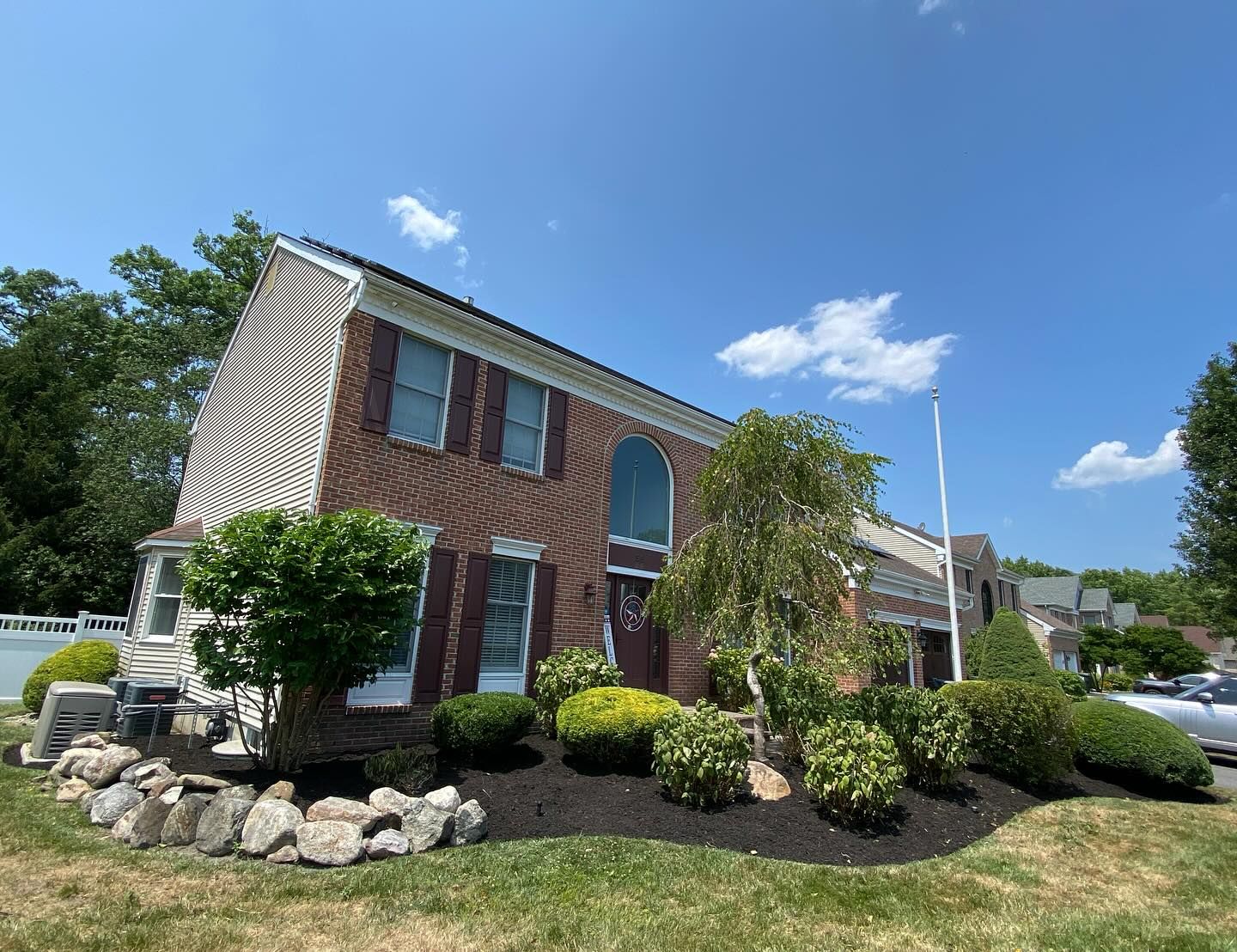 A large brick house with a large lawn in front of it.