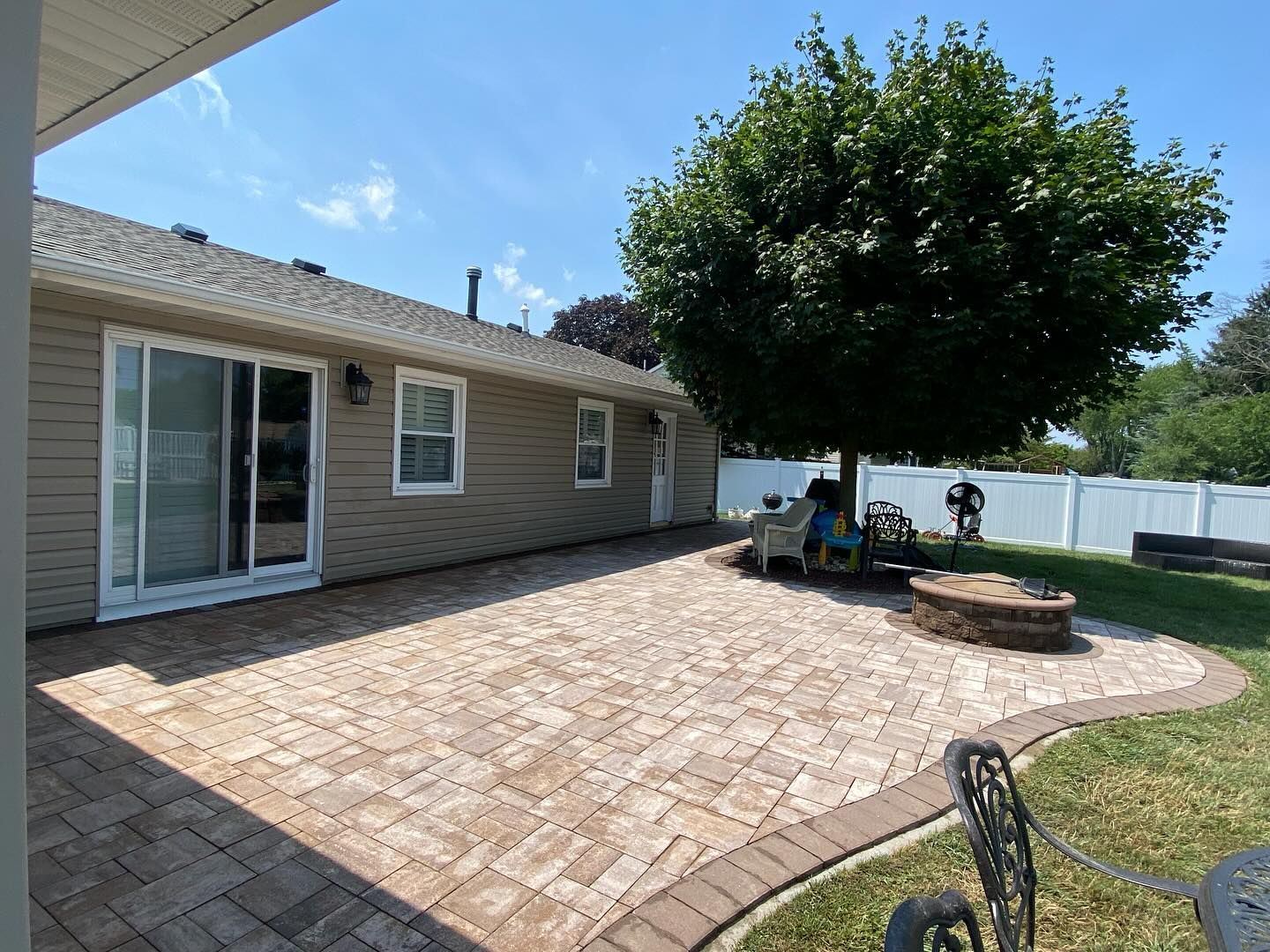 The backyard of a house with a patio and a tree.