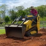 A man is riding a bulldozer on a dirt road.