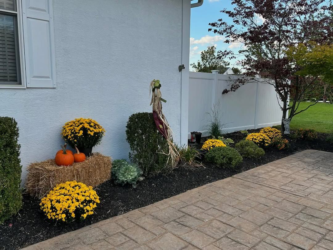 A white house with flowers and pumpkins in front of it