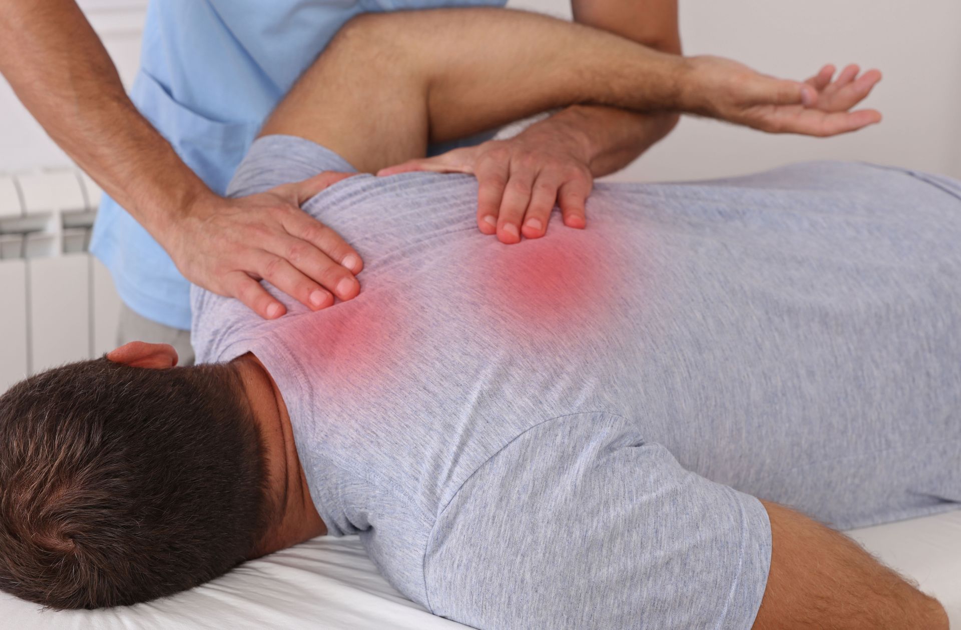 Person receiving a back massage on a massage table, with red areas highlighted, presumably for pain.