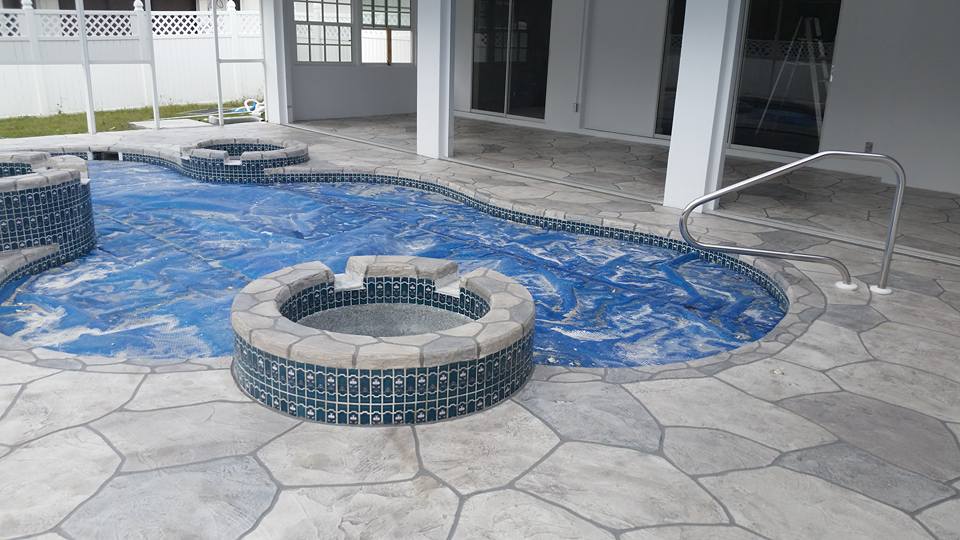 Swimming pool with a blue cover and stone patio.