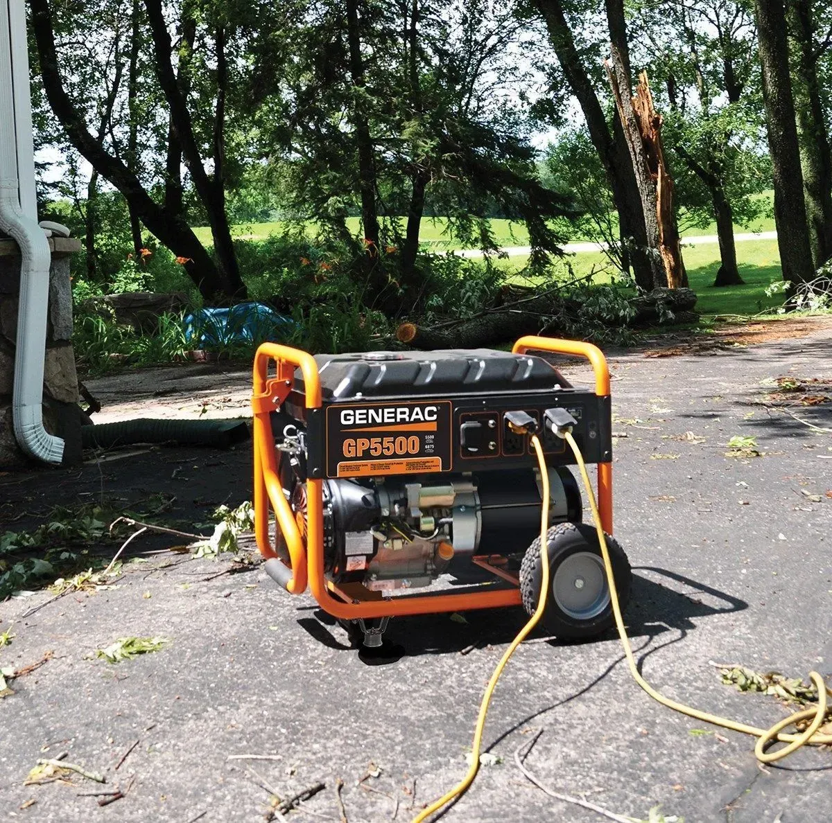 Portable generator in orange frame on asphalt, with hoses and cables in a shaded outdoor yard.