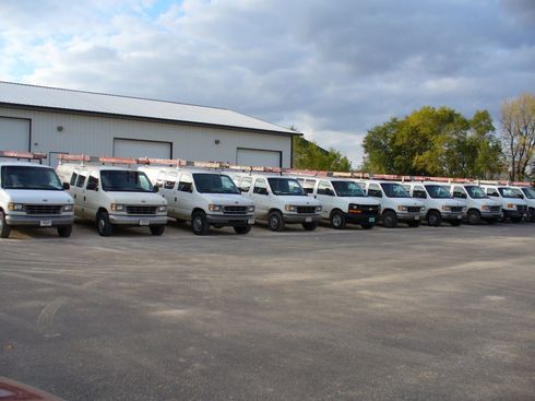 A row of white vans parked in front of a building