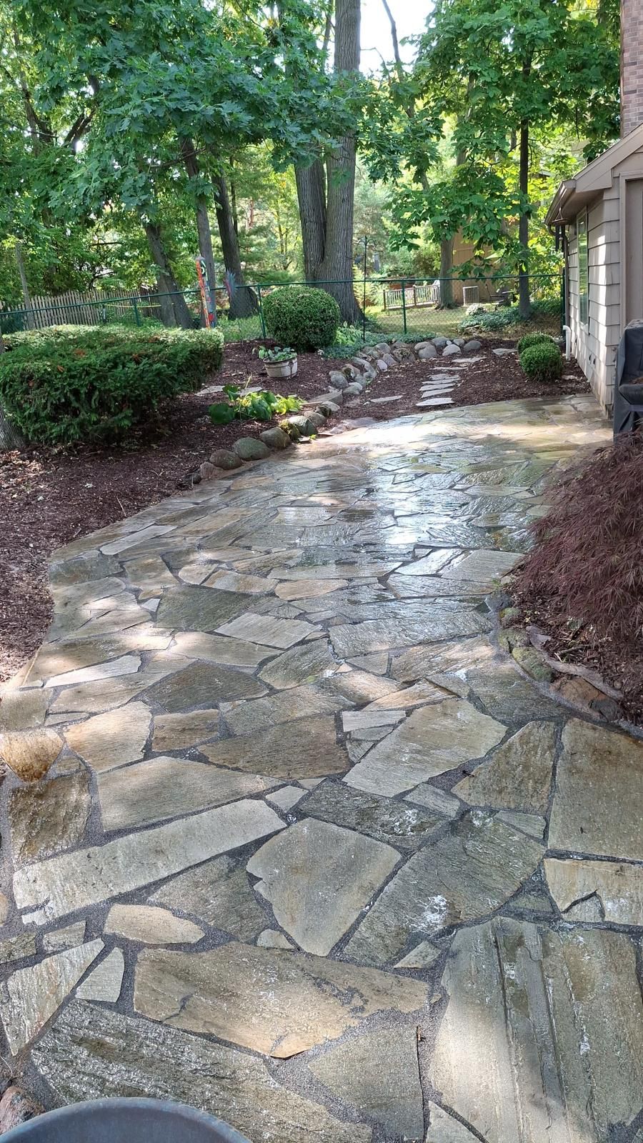 Lush garden path winding through colorful flowerbeds of purple, red, and yellow blooms.