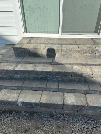 Stone steps leading up to a sliding glass door. The steps are gray bricks with dark border.