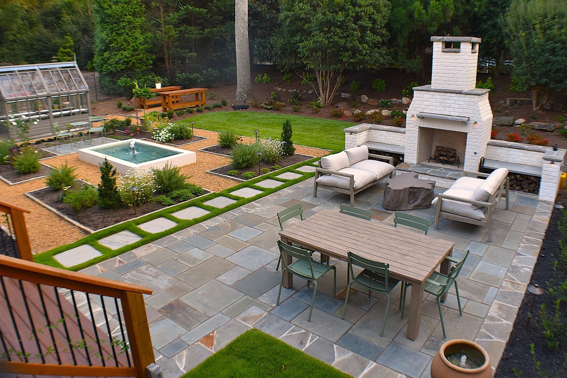 Backyard patio with outdoor fireplace, seating area, dining table, and garden features.