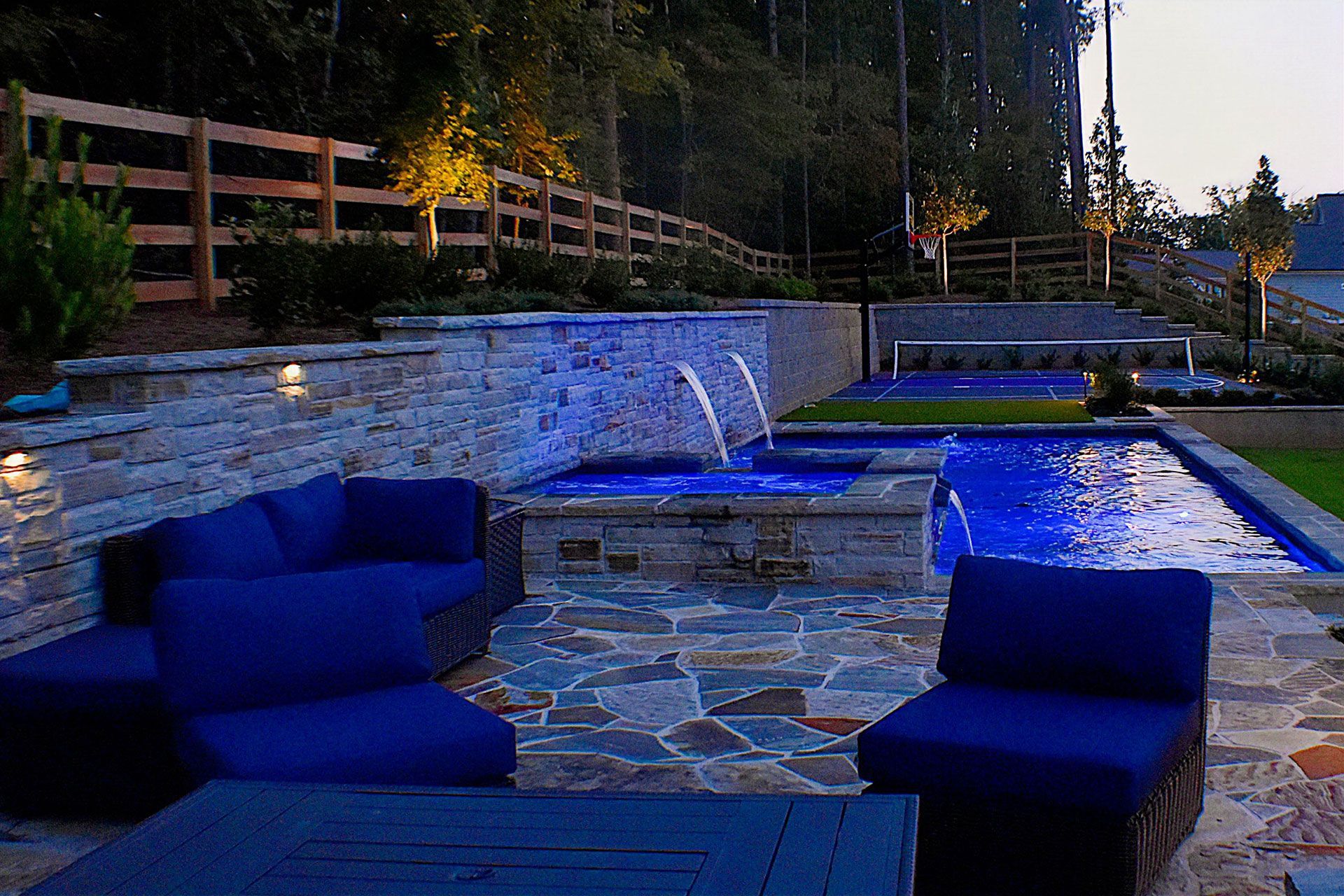 Outdoor patio with blue seating, a tiered water feature, and a fence.