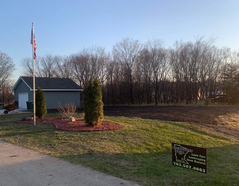 A house with a flag pole in front of it and trees in the background.
