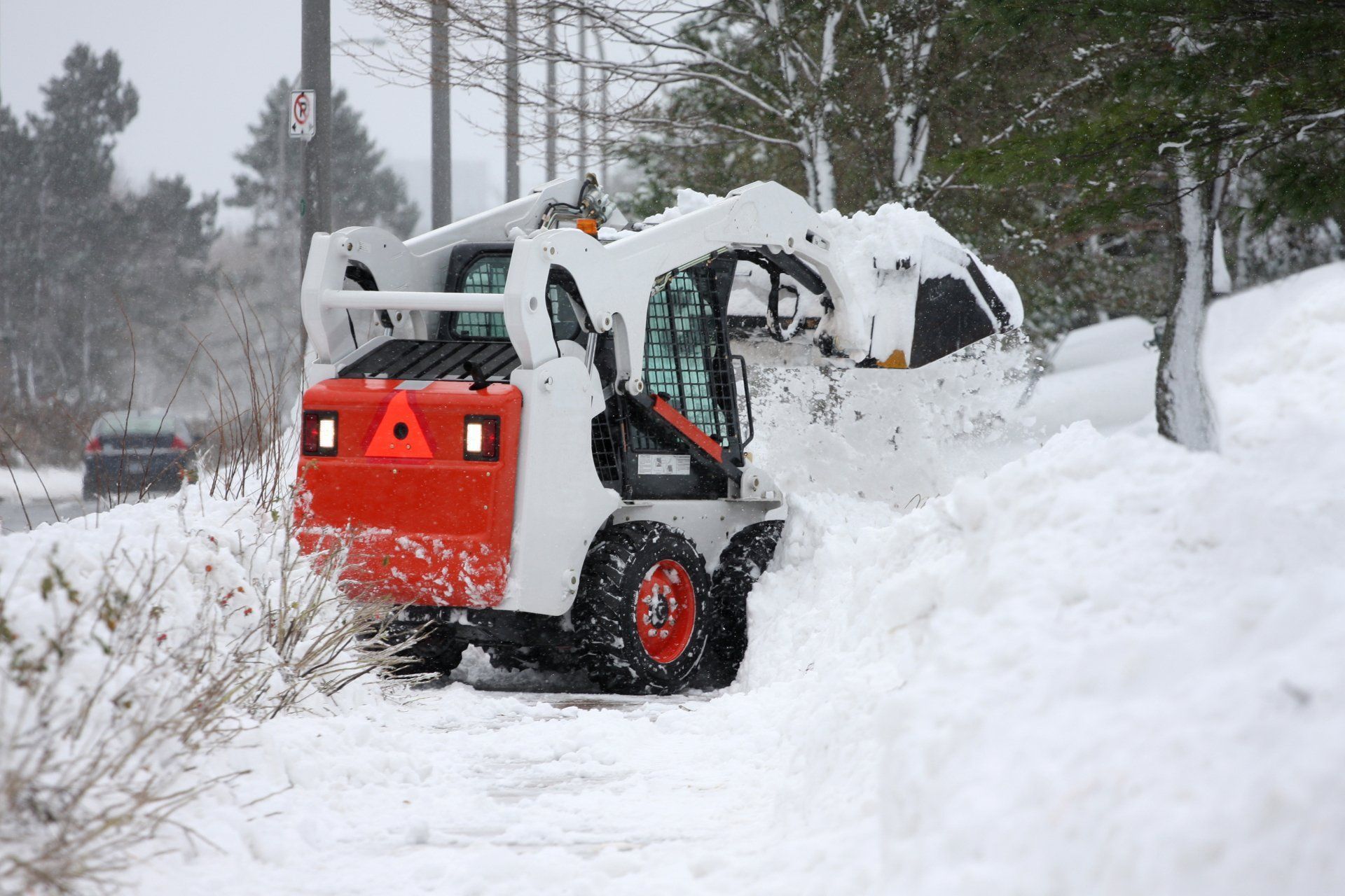 A snow plow is clearing snow from the side of the road.
