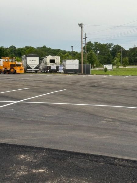 Empty paved parking lot with RVs, a yellow vehicle, and a utility pole.
