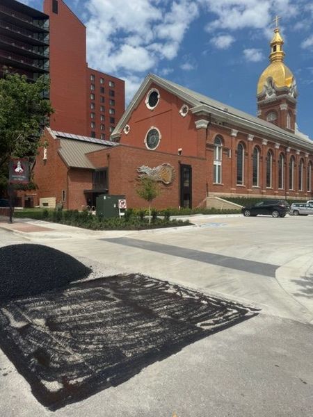 Brick building with gold dome and sidewalk repair, tree, and construction debris.