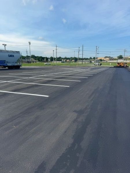 Empty parking lot with freshly painted white lines under a blue sky.