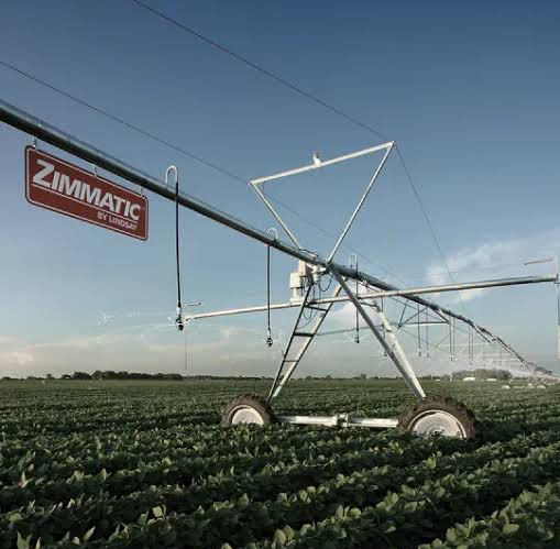 A Zimmatic irrigation system in a green field under a blue sky. 