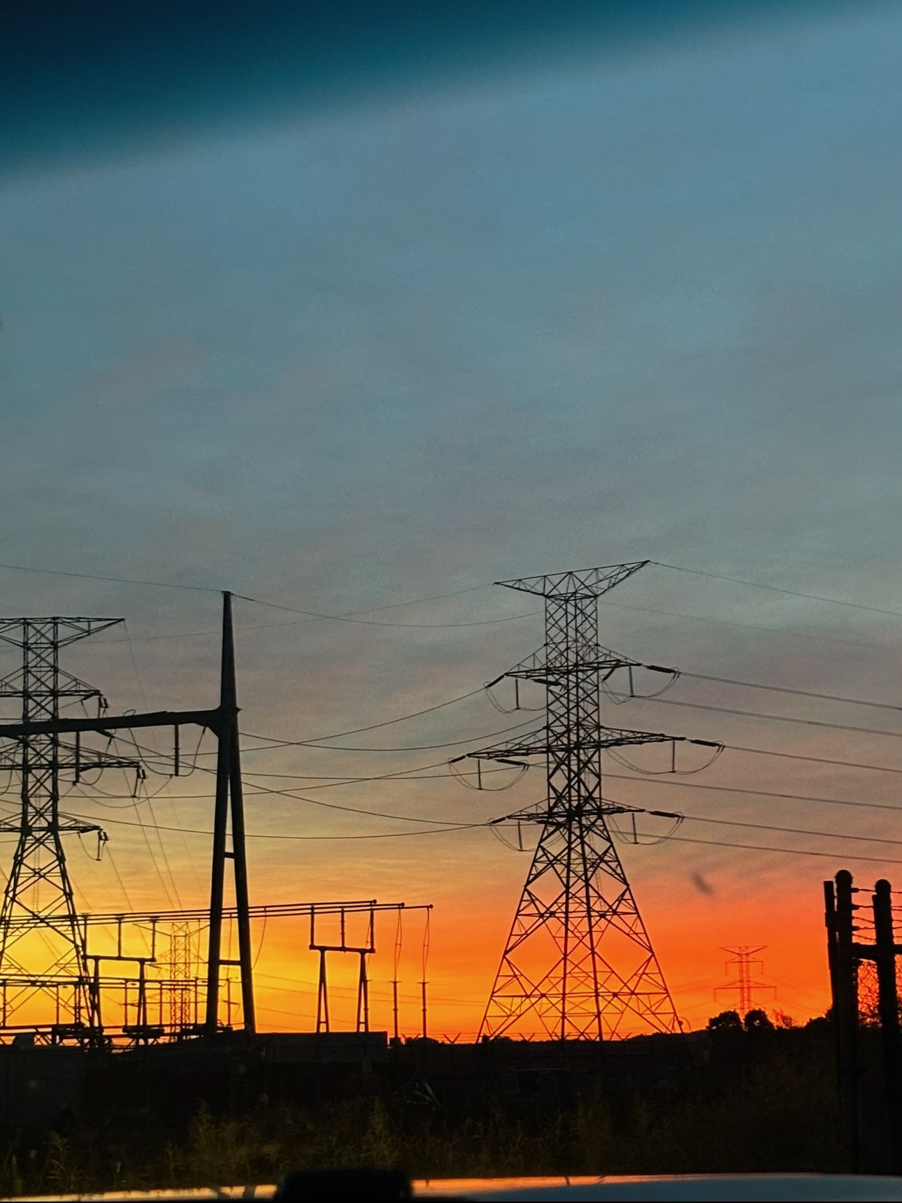 A sunset with a lot of power lines in the foreground