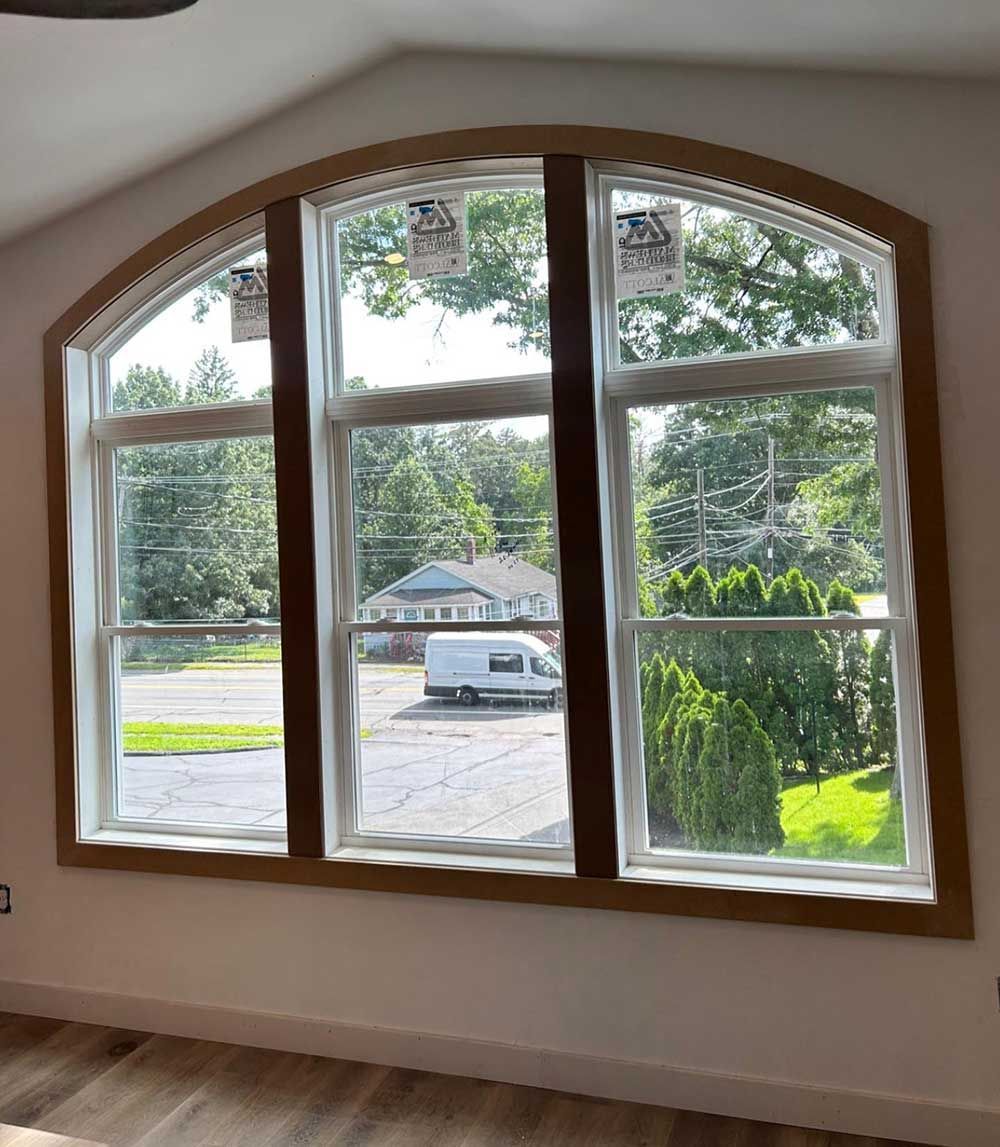 A room with three arched windows and a ceiling fan.