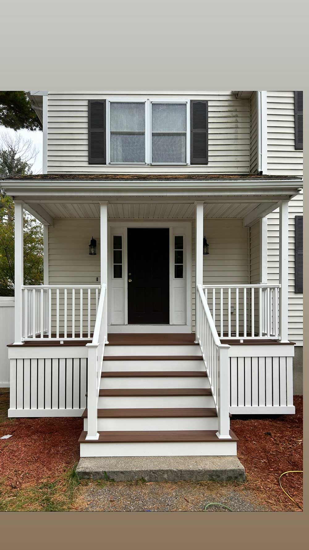 The front of a white house with a porch and stairs.