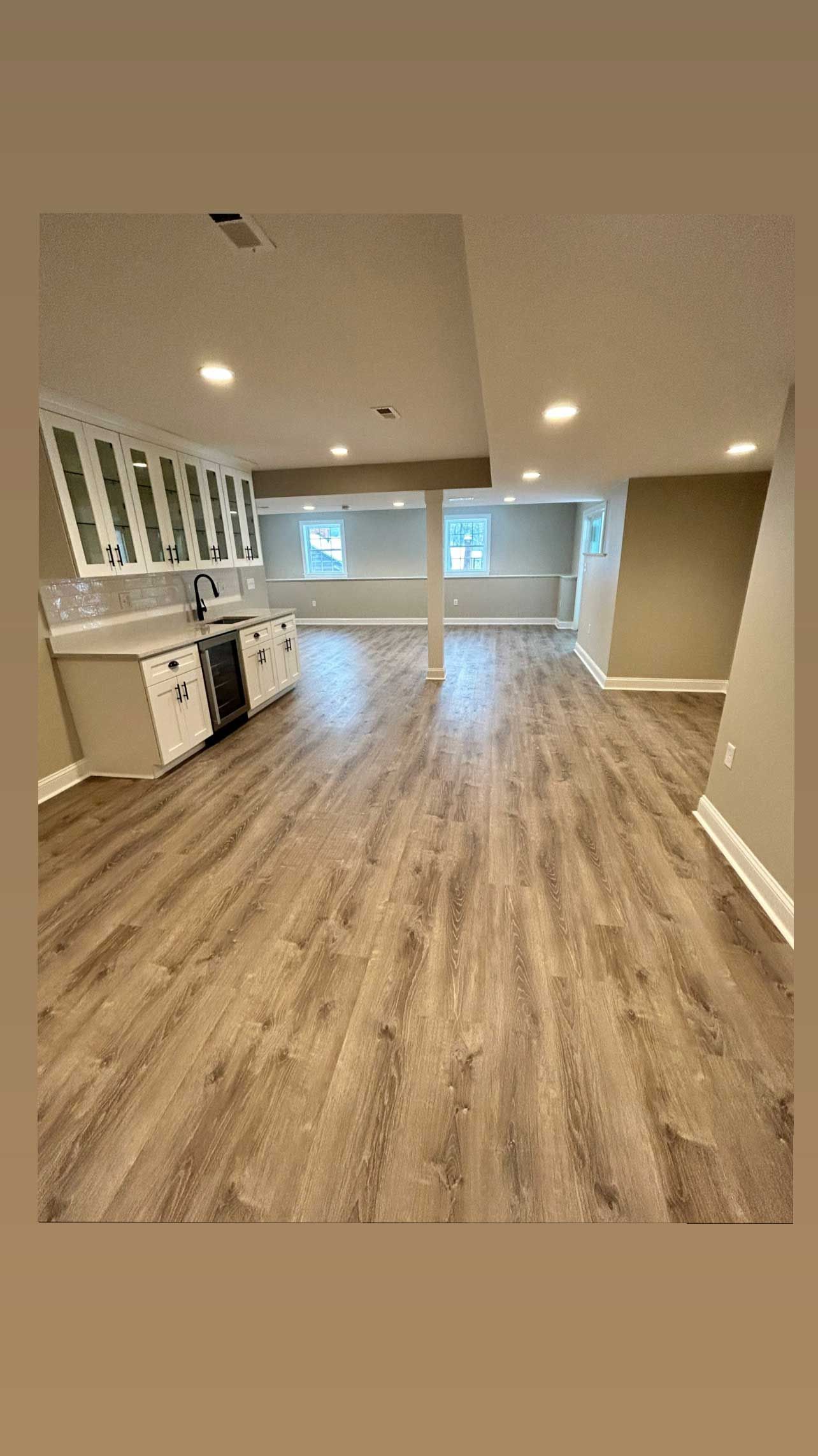 An empty basement with hardwood floors and cabinets.