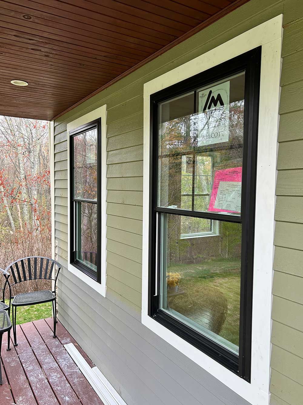 A porch with a chair and two windows on a house.