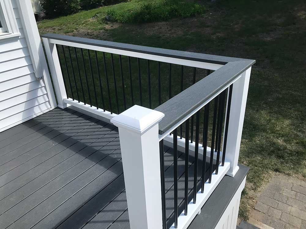 A gray deck with a white railing and a black railing.