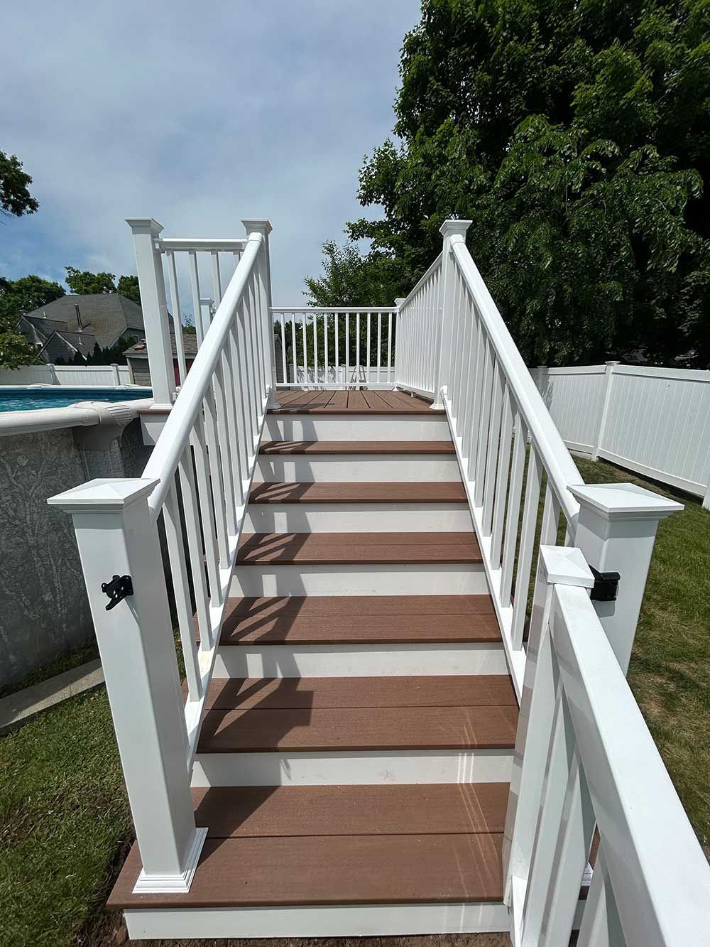 A set of stairs leading up to a deck next to a pool.