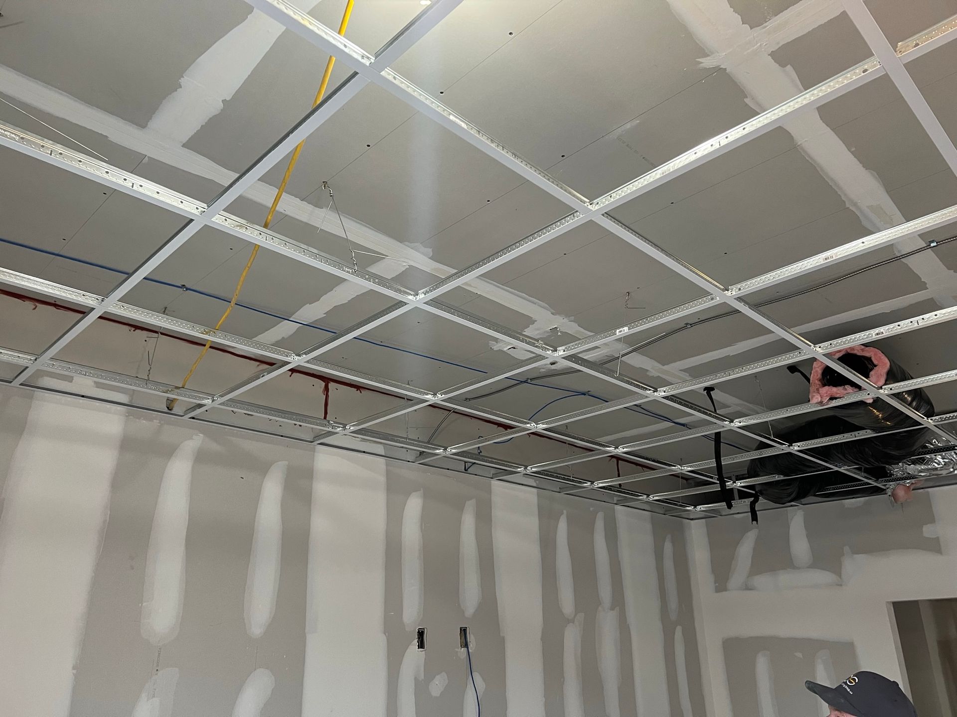 Construction of a ceiling and walls with a metal grid and drywall panels.