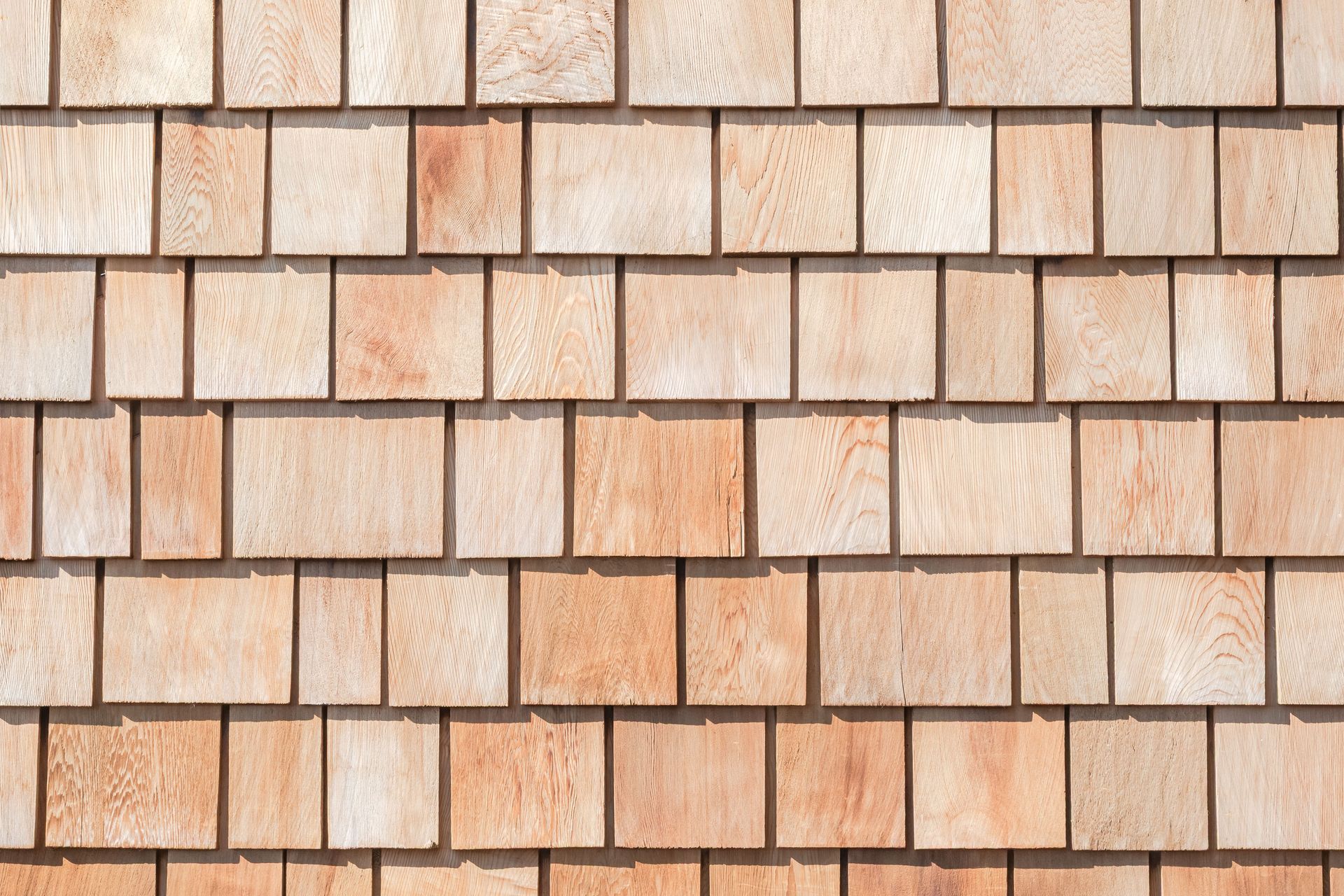 Cedar wood shingle siding with overlapping rectangular tiles in natural wood tones.