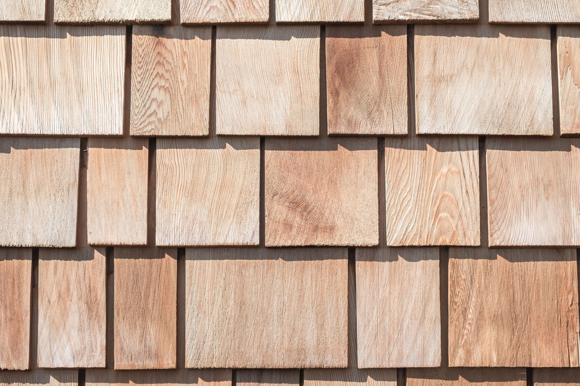Wooden shingles arranged in a staggered pattern, showcasing natural wood grain and varying shades of brown.