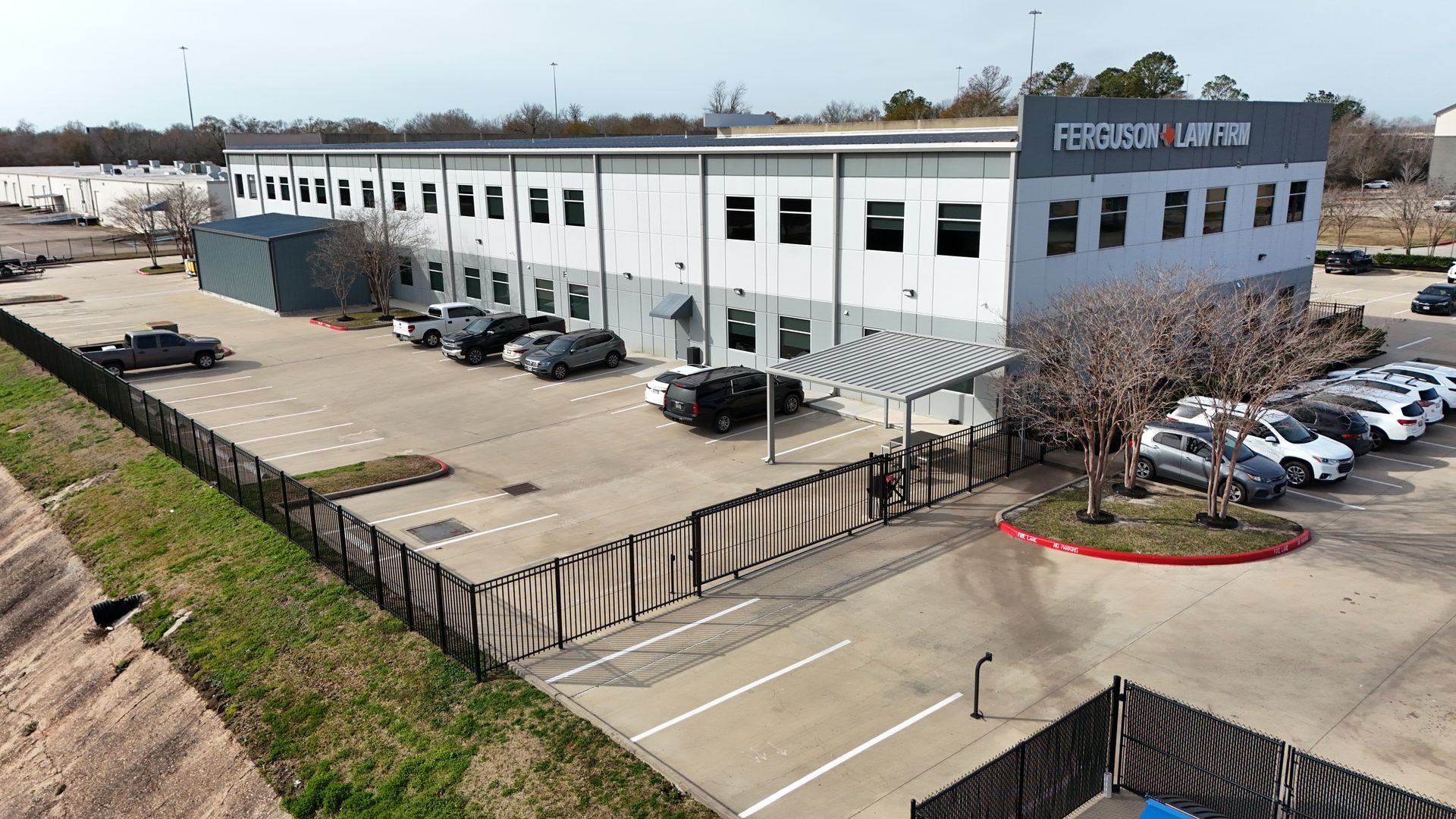Exterior of H-Town Customs building with parked cars and a fenced parking area.