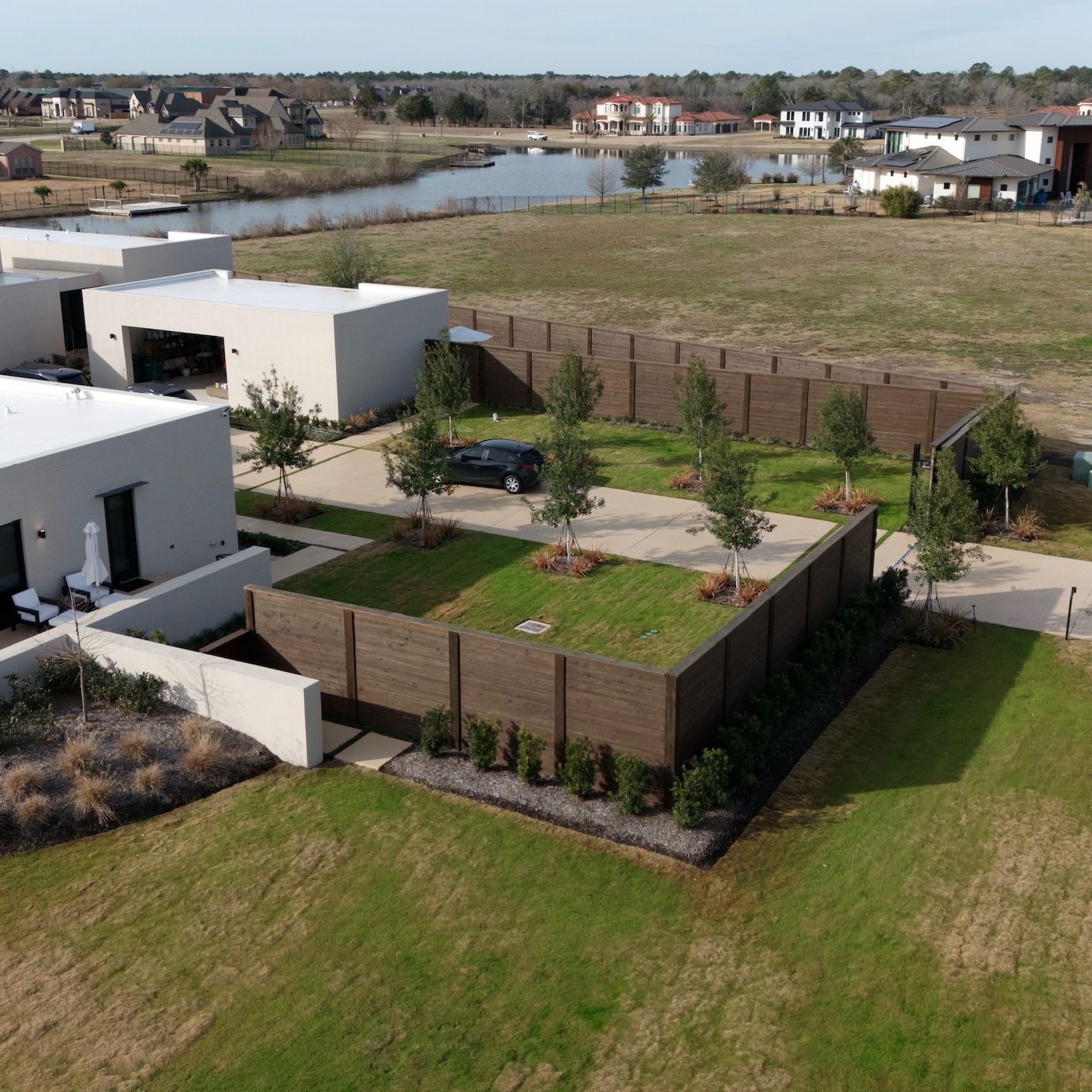 Modern homes with wooden fences and green space near a lake.