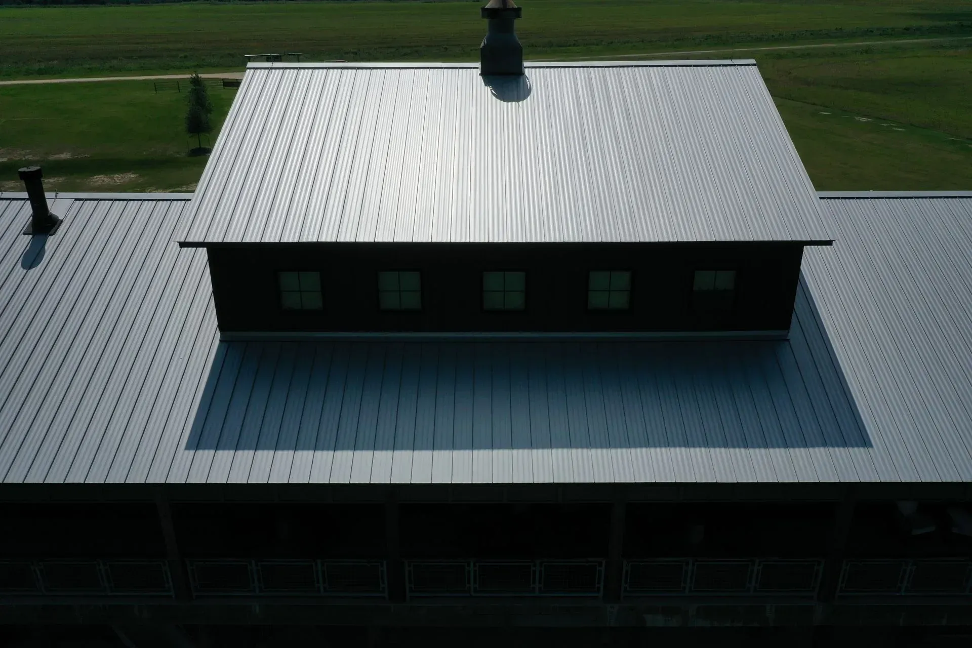 Overhead view of a building with a metal roof and a darker upper section with windows, chimney.