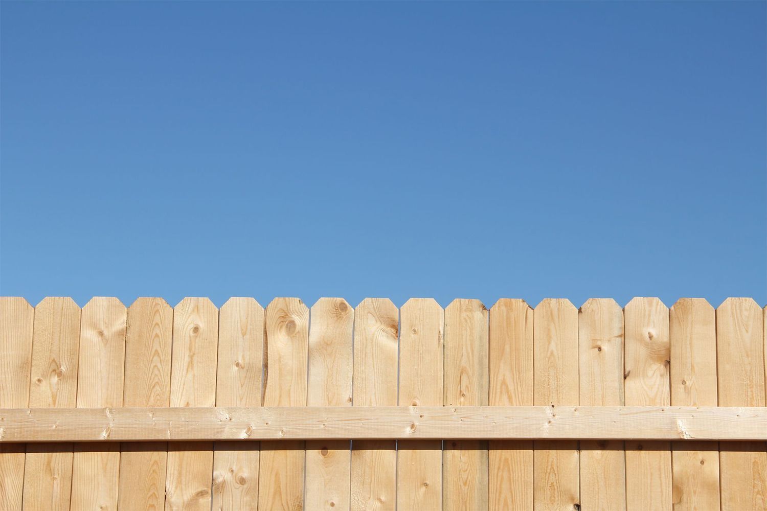 Wooden fence against a bright blue sky.
