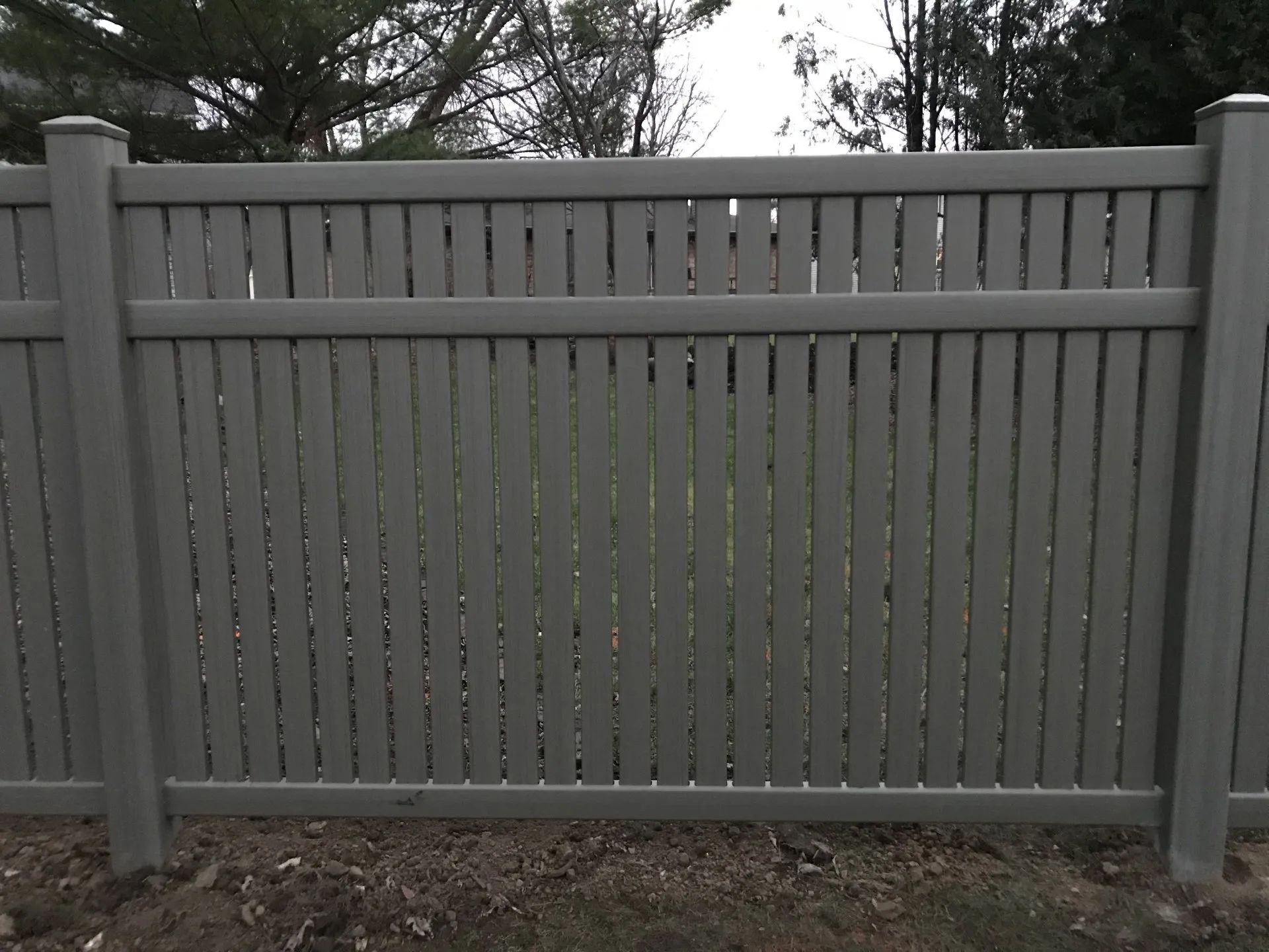 Gray vinyl privacy fence with vertical slats.