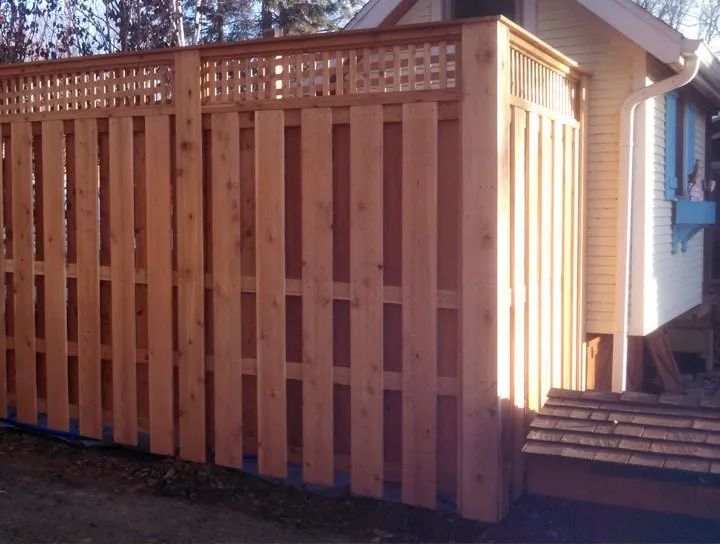 Wooden privacy fence with lattice detail; next to a light-colored house.