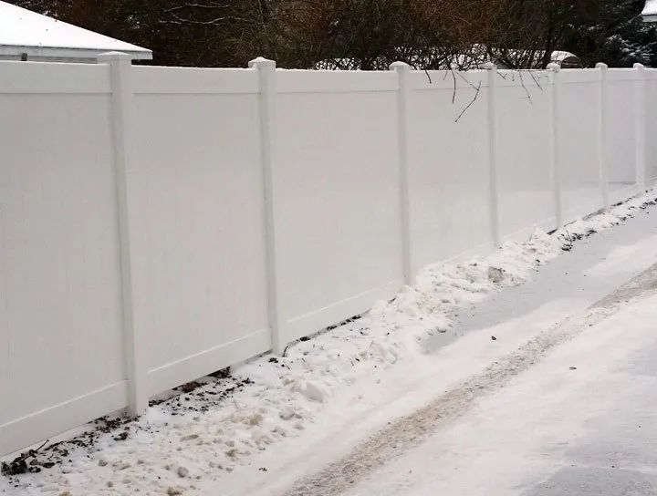 White vinyl fence along a snow-covered roadside.