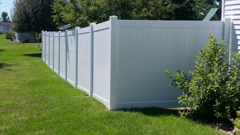 White vinyl privacy fence in a grassy yard.